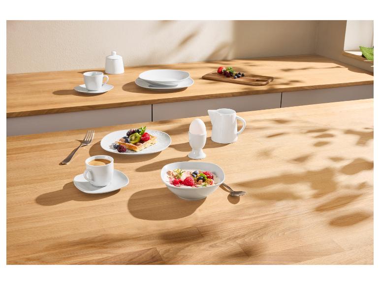 Frühstück mit Fruchtwaffel, Joghurt, Kaffee und Ei auf einem Holztisch.
