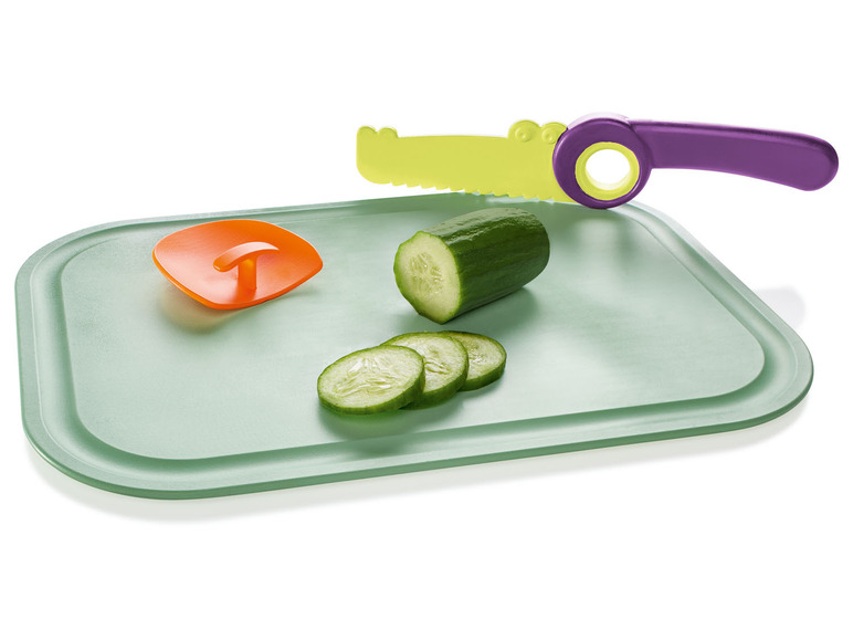 Ein grünes Schneidebrett mit einer Gurke, einem Krokodilmesser und einem orangen Fingerspitzenschutz.