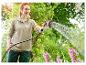 Eine Frau gießt Blumen mit einem Gardena Gartenschlauch.