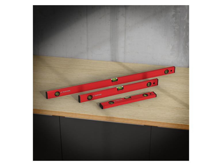 Drei rote Wasserwaagen von Parkside auf einem Holztisch.