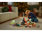 Kind spielt mit Zug und Dinosauriern in einem weihnachtlichen Wohnzimmer.