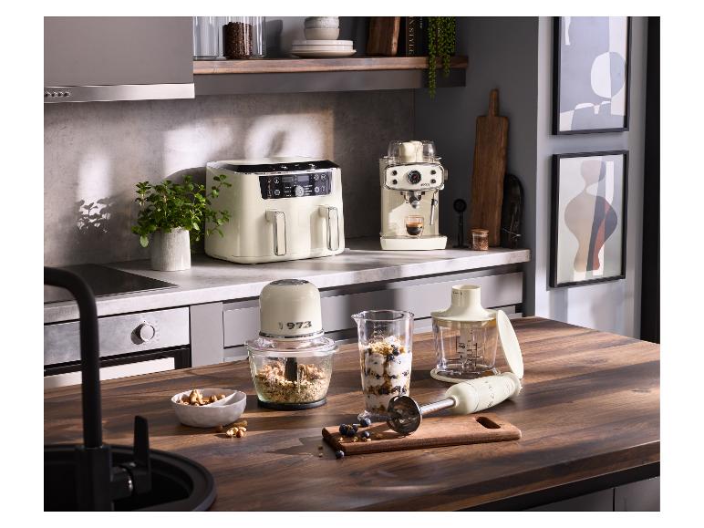Küche mit cremefarbener Heißluftfritteuse, Espressomaschine und Mixer auf einer Holztheke.