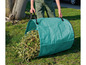 Eine Person trägt einen grünen Gartensack voller Äste und Blätter.