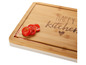 Ein Holzschneidebrett mit der Aufschrift 'Happy Kitchen' und Tomaten.