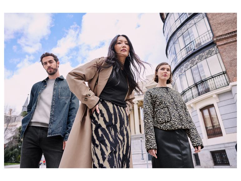 Models posieren in stylischer Kleidung vor einem Gebäude.