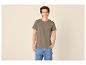 Junger Mann in khakifarbenem T-Shirt und blauen Jeans
