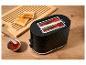 Schwarzer Toaster mit Toastbrot, Marmelade und einem Holzschneidebrett.