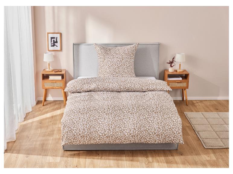 Beige-weiße Blumen-Bettwäsche auf modernem Bett.