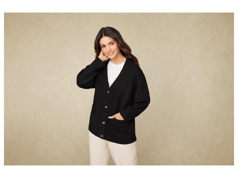 Eine Frau trägt einen schwarzen Pullover und eine beige Hose.