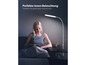 Eine Frau liest auf dem Sofa ein Buch, neben ihr steht eine weiße Stehlampe.