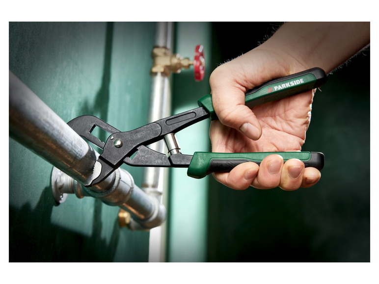 Eine Hand hält eine Parkside Wasserpumpenzange an einem Metallrohr fest.