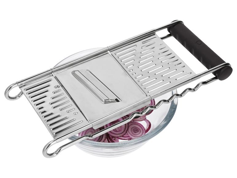 Küchenmandoline aus Metall mit schwarzen Griffen über einer Glasschale mit geschnittenen roten Zwiebeln.