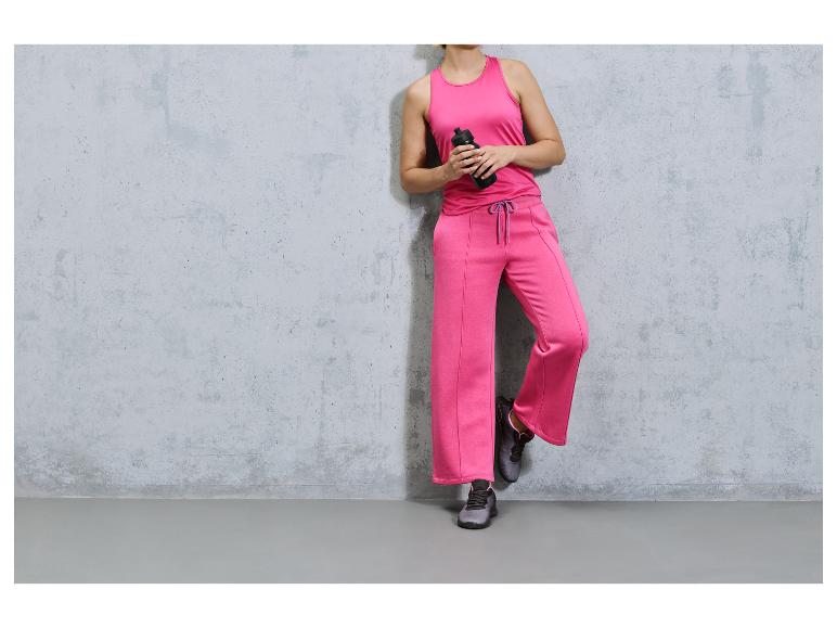 Eine Frau trägt rosafarbene Sportkleidung und schwarze Turnschuhe
