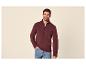 Mann in einem bordeauxroten Reißverschluss-Pullover und Jeans.
