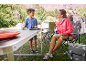 Frau und Kind campen mit Klapptisch, Campingstühlen und Zelten.