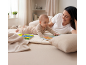 Mutter und Baby spielen auf dem Boden, Baby blättert in einem Bilderbuch.