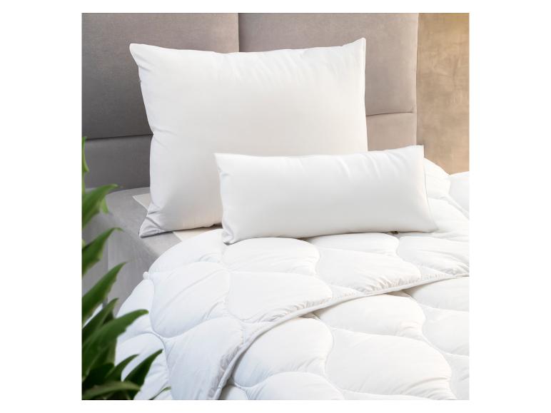 Weiße Bettdecke, Kissen und Kopfkissen auf einem Bett.