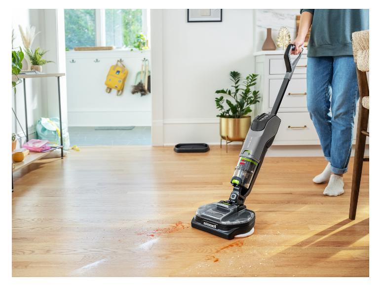 Person reinigt Holzboden mit einem Bissell SpinWave Vac, der Verschüttetes aufsaugt.