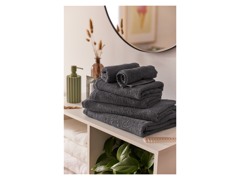 Ein Stapel dunkelgrauer Handtücher auf einem Badezimmerregal.