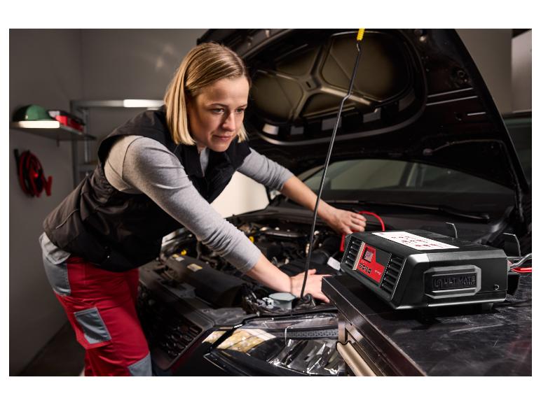 Frau arbeitet an einem Automotor, mit einem Ultimate Batterieladegerät im Vordergrund.