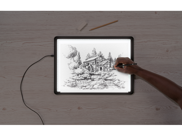 Hand zeichnet eine detaillierte Skizze einer Wassermühle auf einem Leuchttisch.