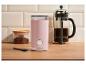 Rosa Kaffeemühle, French Press und gemahlener Kaffee auf einer Holztheke.