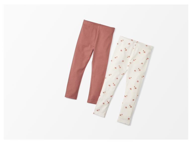 Zwei Leggings für Mädchen: eine rosa und eine mit Blumenmuster.