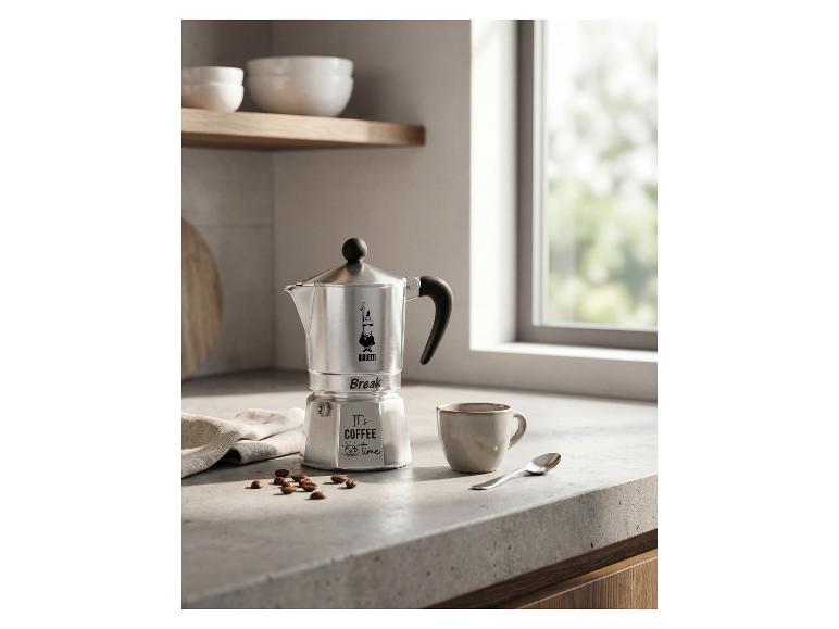 Silberne Kaffeemaschine mit „It's coffee time“-Schriftzug und einer Tasse auf einer Küchenarbeitsplatte.