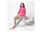 Lächelnde Frau in rosa Pyjama mit Leopardenmuster, auf einem Stuhl sitzend.