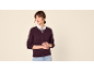 Frau in einem bordeauxroten Cardigan über einem weißen Hemd, mit hellen Jeans.