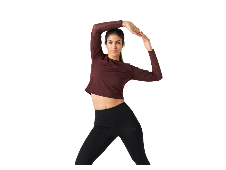 Frau in einem weinroten Langarm-Shirt und schwarzen Leggings.
