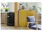 Schwarzer Minikühlschrank und gelbe Schränke neben einem grauen Sessel.
