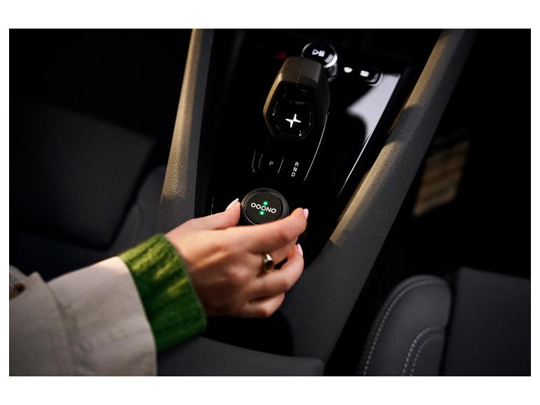 Frau stellt ein rundes Gerät mit grünen Lichtern im Auto ein.