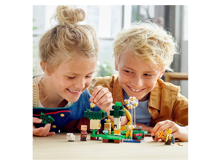Zwei Kinder spielen mit einem LEGO Minecraft Set mit einem Baum und Figuren.