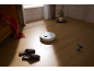 Weißer Saugroboter auf Holzboden im Wohnzimmer.