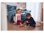 Zwei Kinder spielen mit Holzspielzeug auf einem Teppich.
