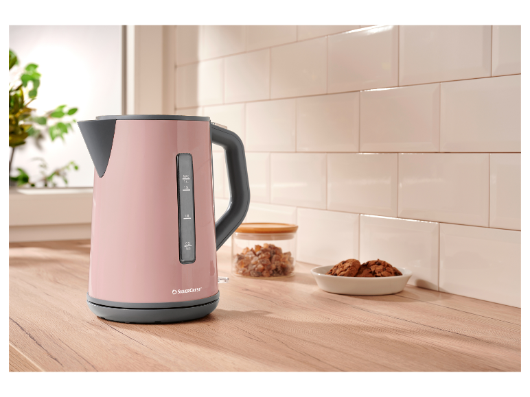 Ein rosa SilverCrest Wasserkocher auf einer Holztheke.