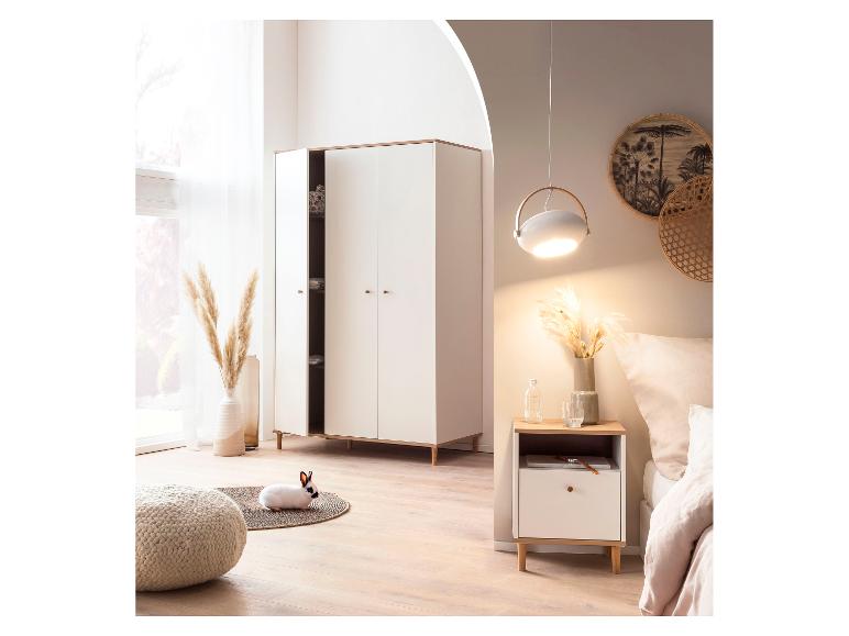 Schlafzimmer mit weißem Kleiderschrank, Nachttisch, Bett und einem Kaninchen auf einem Teppich.