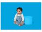 Baby in blauem Strickstrampler sitzt neben einem blauen Zylinder.