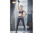 Eine Frau in Sport-BH und Leggings trainiert mit einer Hantel.