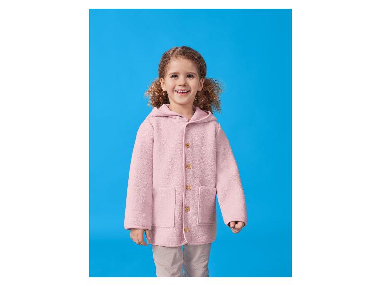 Lächelndes Mädchen in rosa Kapuzenjacke und beiger Hose