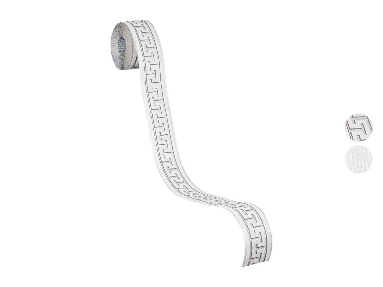 Weißes Dekoband mit silbernem Mäandermuster, von einer Spule abgerollt.