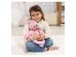 Mädchen hält eine Babypuppe in rosa Kleidung, sitzend auf einem weißen Teppich.