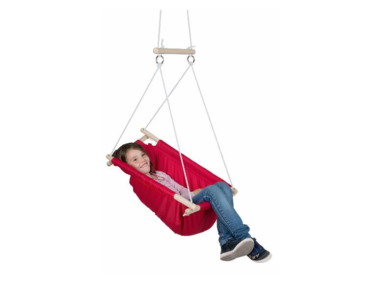 Ein lächelndes Mädchen schaukelt in einer roten Stoffschaukel