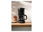 Schwarze Filterkaffeemaschine mit frisch gebrühtem Kaffee in einer modernen Küche.