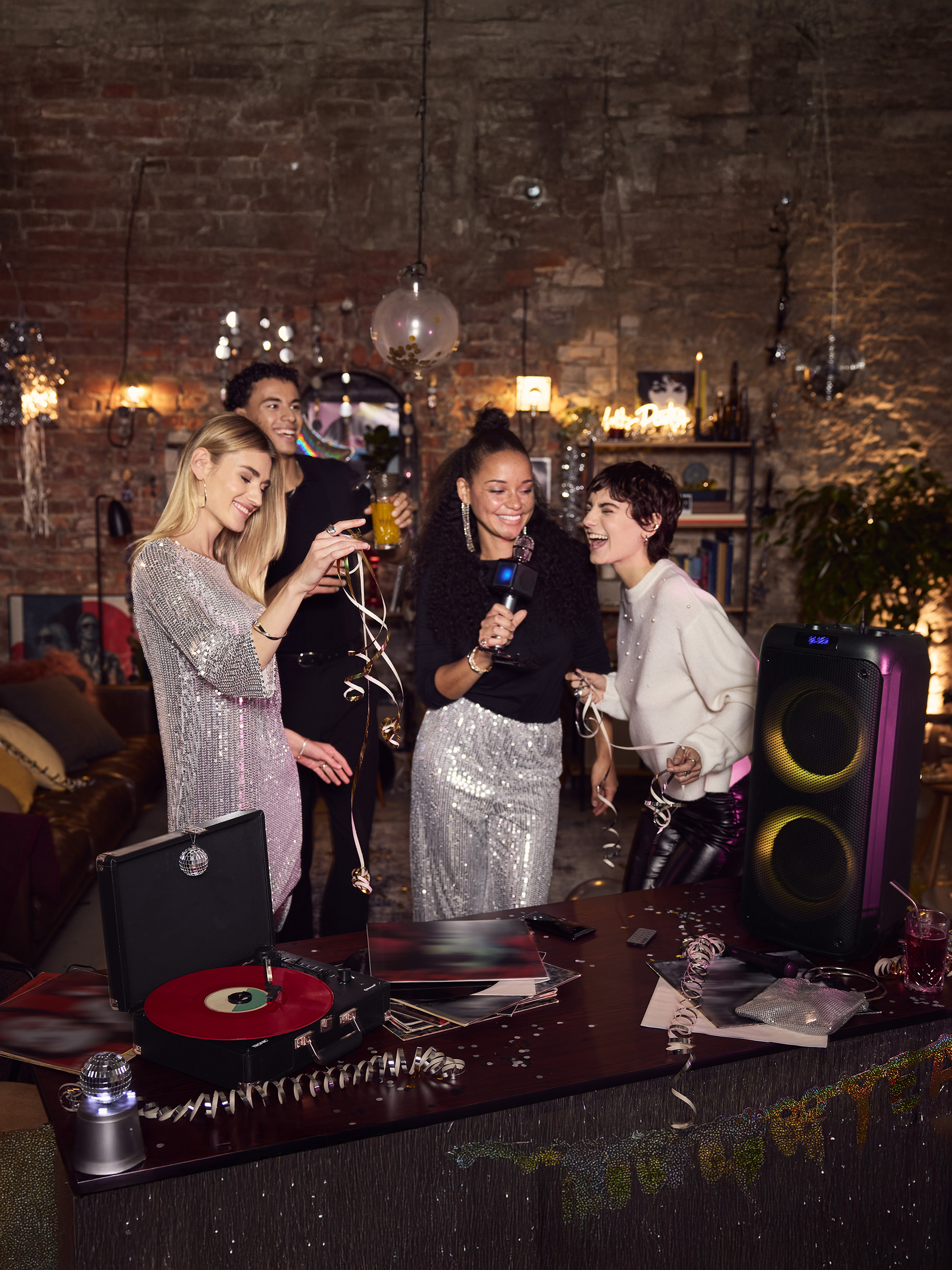 Freunde singen Karaoke mit Lautsprecher und Plattenspieler auf einer Party.