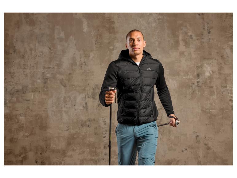 Mann in einer schwarzen Jacke mit Kapuze und Wanderstöcken.