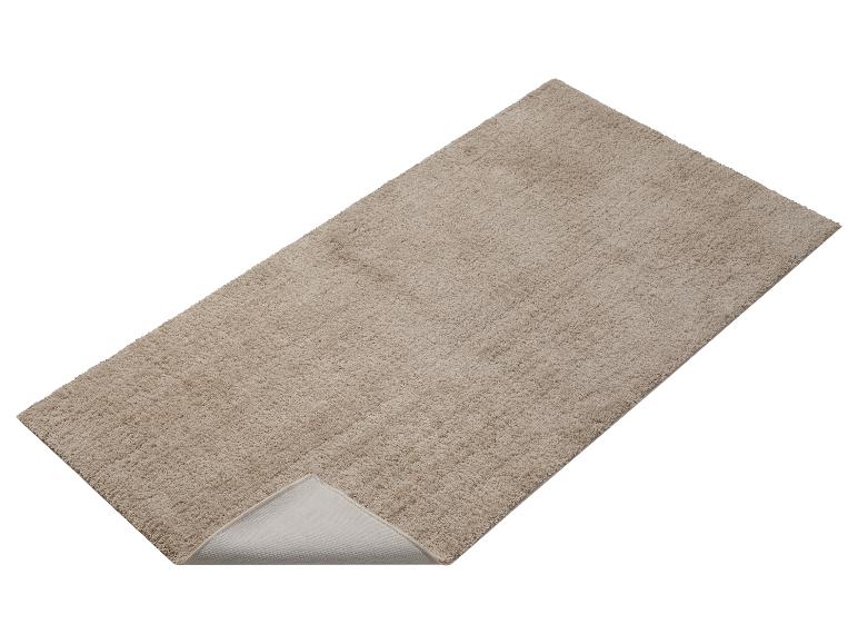 Eine beige Badematte mit rutschfester Unterseite.