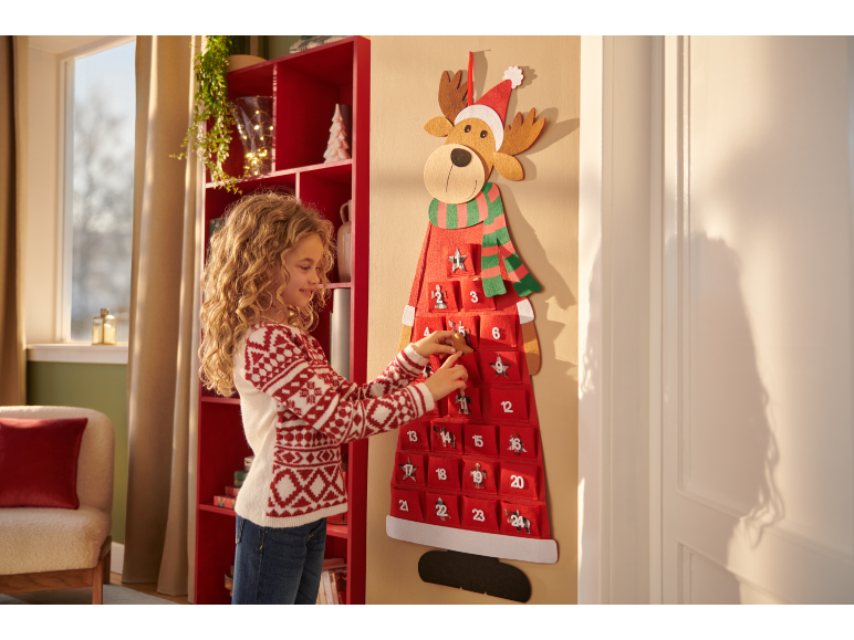 Ein Mädchen interagiert mit einem festlichen Rentier-Adventskalender, mit Zahlen 1-24.