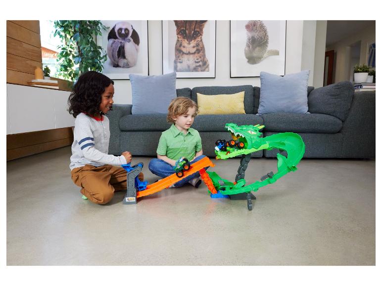 Zwei Jungen spielen mit einem Monstertruck-Streckenset mit einem grünen Drachen.